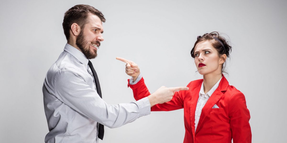 Two corporate professionals are pictured. They have exaggerated body language, suggesting that they are having difficult conversations. This image aims to visualise the topic of the blog which describes why difficult conversations might go wrong and how to overcome this with effective communication.
